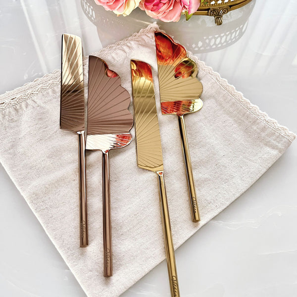 Záhra Duo cake server set featuring elegant gold and copper finishes on a textured linen napkin, reflecting luxury and style.