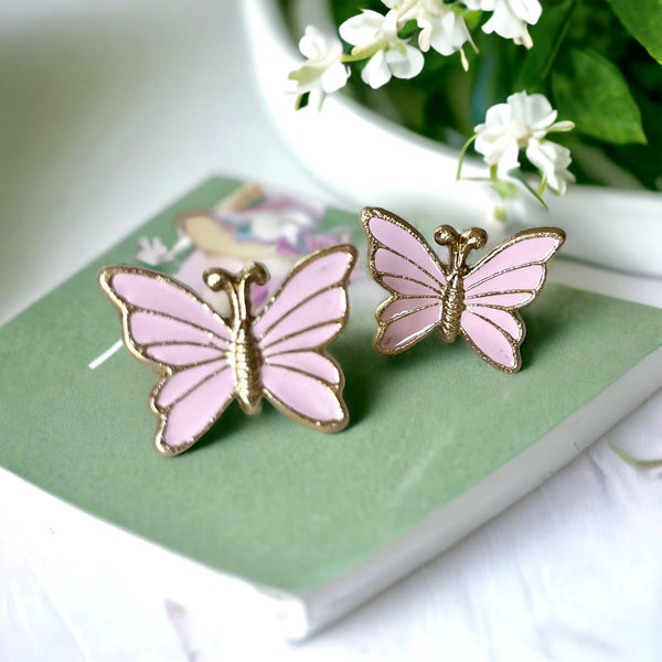 The image shows elegant butterfly-shaped napkin rings with a pastel pink enamel finish, made from metal. These charming rings add a sophisticated touch to table settings, perfect for any occasion.