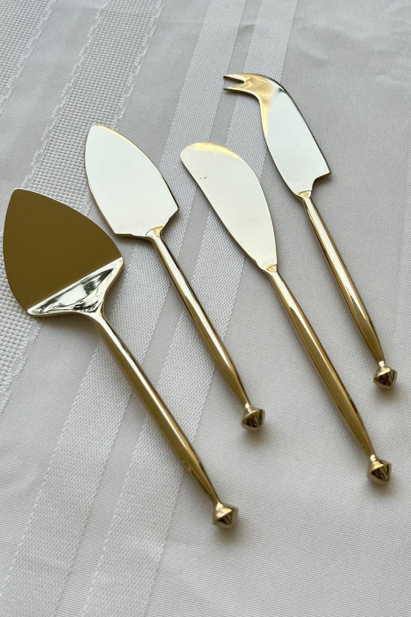 Aiza Stainless Steel Cheese Knife Set featuring four elegant brass-toned knives with polished handles and precision-crafted blades, perfect for sophisticated dining.