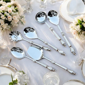 Amála Chandi set of six serving spoons displayed elegantly on a table setup with floral arrangements and white dinnerware, showcasing intricate brass handle detailing.