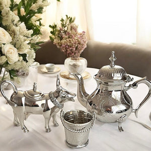 A beautifully crafted cow creamer tea set featuring a cow-shaped creamer, an elegant kettle, and a bucket-shaped sugar pot, all made from shiny silver, perfect for adding charm to your tea table.