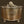 Close-up of a Zen Brass Storage Box with ornate floral engravings and a snail-shaped handle on the lid, set against a dark background. The brass box rests on delicately crafted feet, emphasizing its luxurious and detailed craftsmanship.