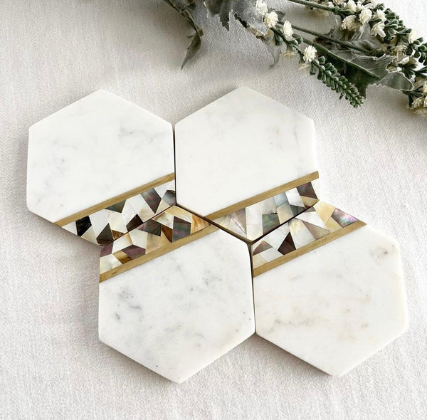 Hexagon Marble Coasters made from polished white marble, featuring intricate brass and mother of pearl inlays. A luxurious addition to any table setting or decor.