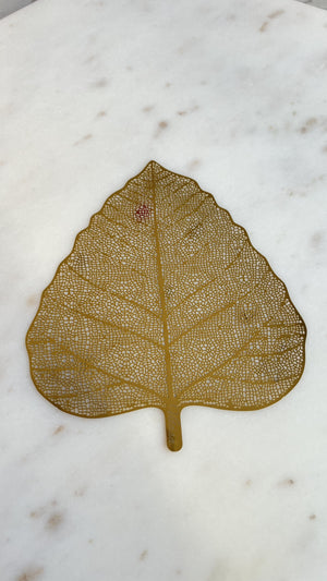 A delicate Stainless Steel Bookmark shaped like a "bodhi" leaf with intricate laser-cut patterns, showcasing its artistic design. This elegant piece also serves as a versatile mug cover, blending style with functionality.
